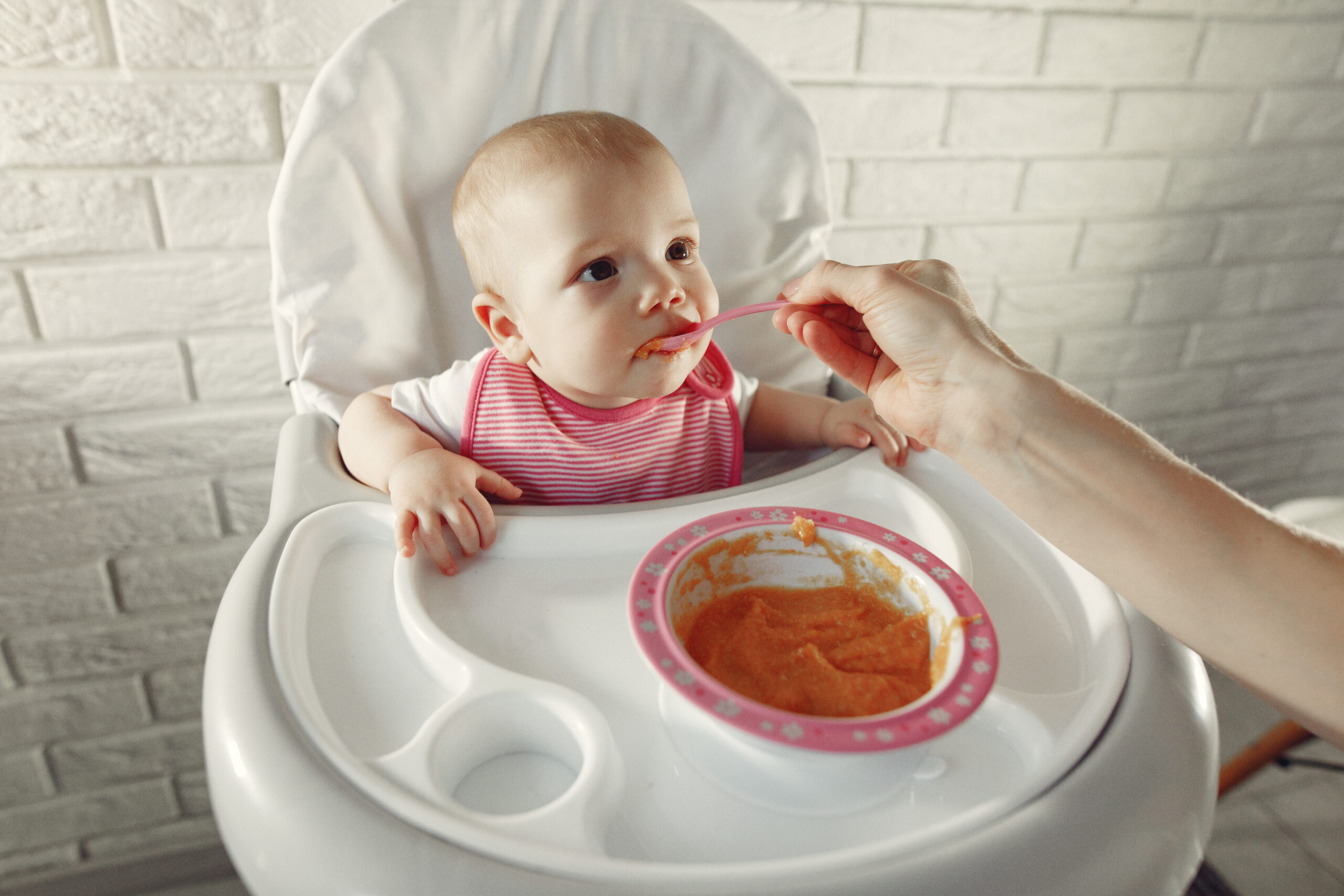 Mother feeds the little baby in a kitchen